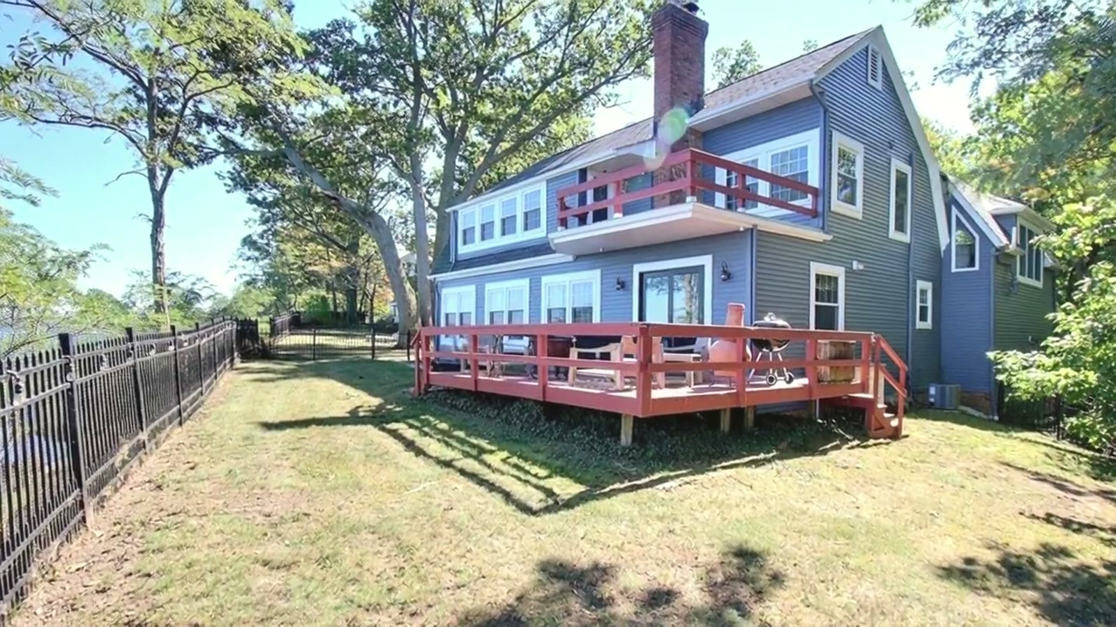 A blue 1895 gambrel-roof house on a sunny lawn above Lake Erie
